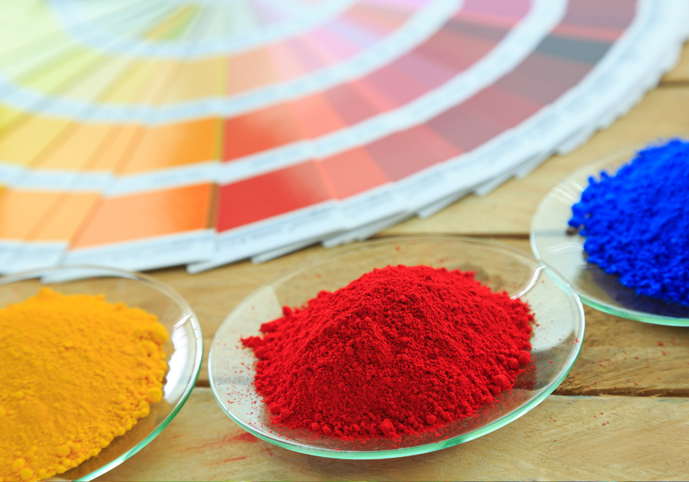 Leuchtende Pulverbeschichtungspigmente vor Farbfächern auf Holztisch in Stuhr